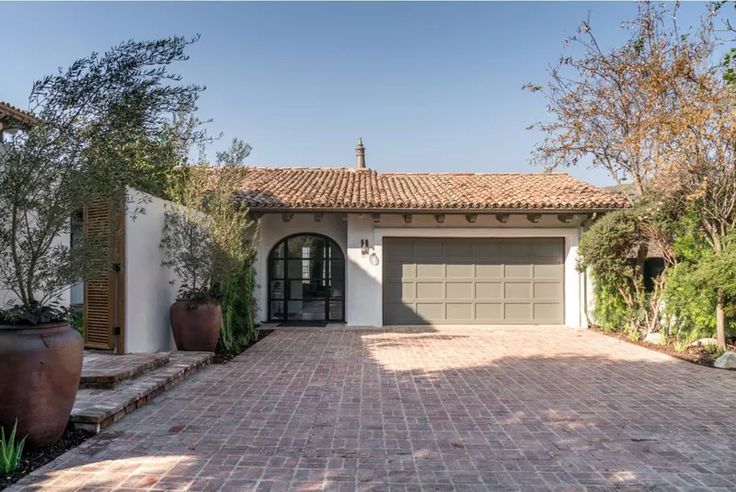 a house with a driveway in front of it and two large planters on the side