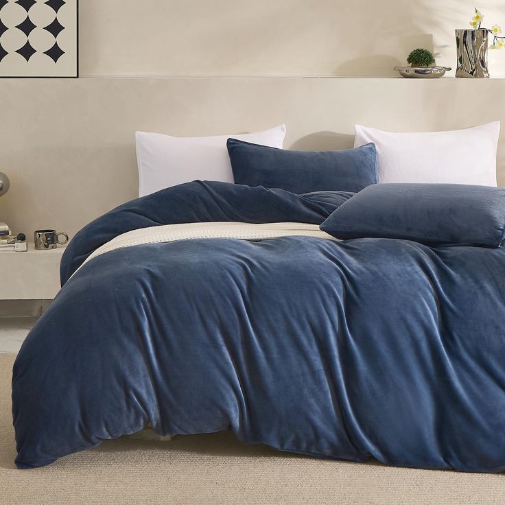 a bed with blue comforter and pillows in a bedroom setting on top of a carpeted floor