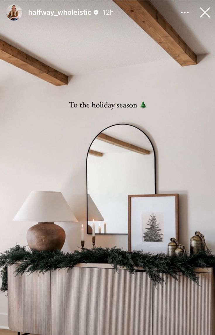 a living room with a large mirror and christmas decorations on the mantle, next to a lamp