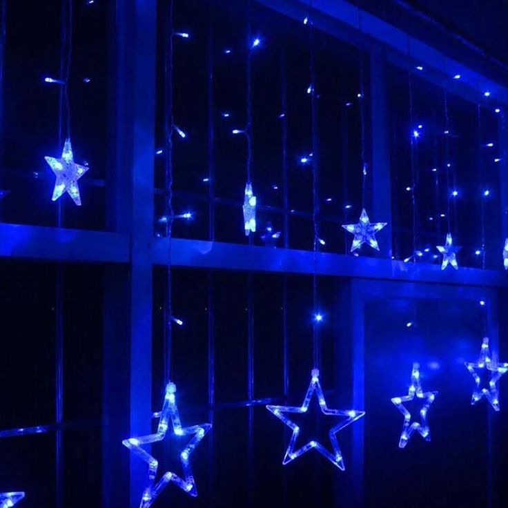 blue lights are hanging from the ceiling in front of a window with stars on it