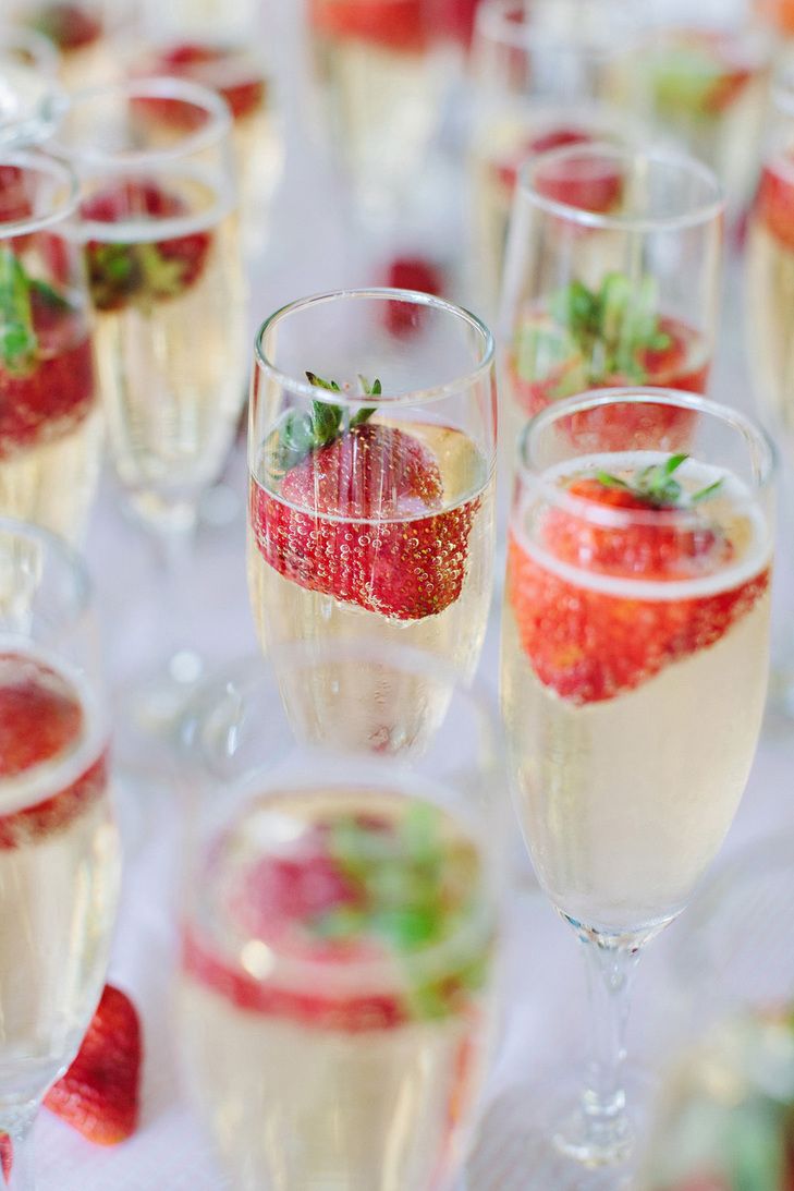 several glasses filled with different types of drinks and garnished with strawberries on the table