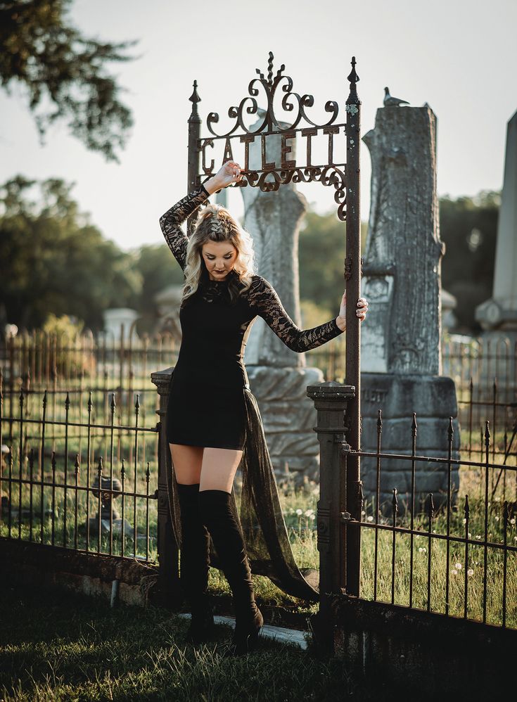 a woman standing in front of a gate with her hands on her head and legs crossed