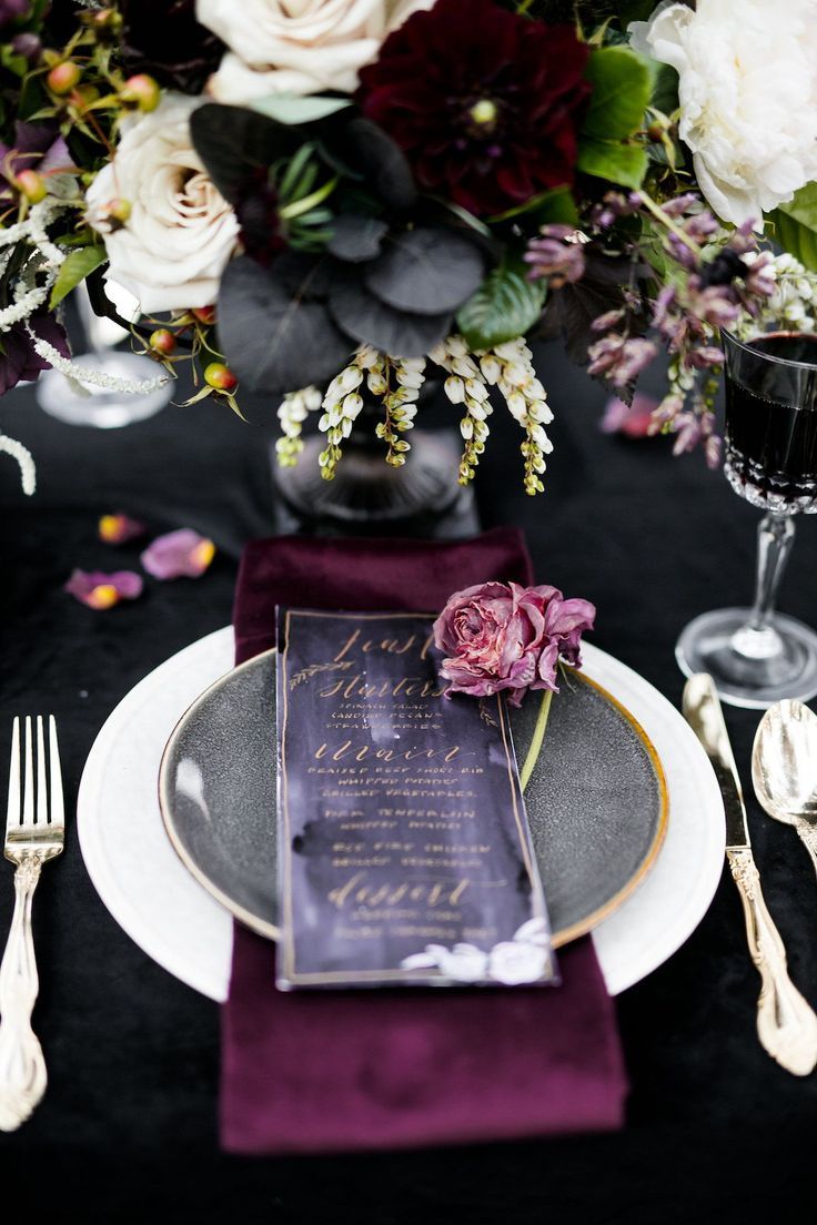 the table is set with purple and white flowers, silverware, and wine glasses