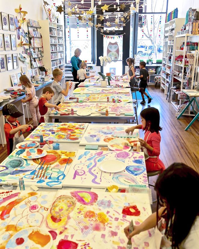 children are sitting at tables with paintings on them