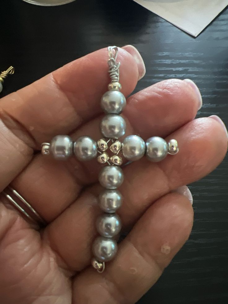 a person holding a cross made out of pearls