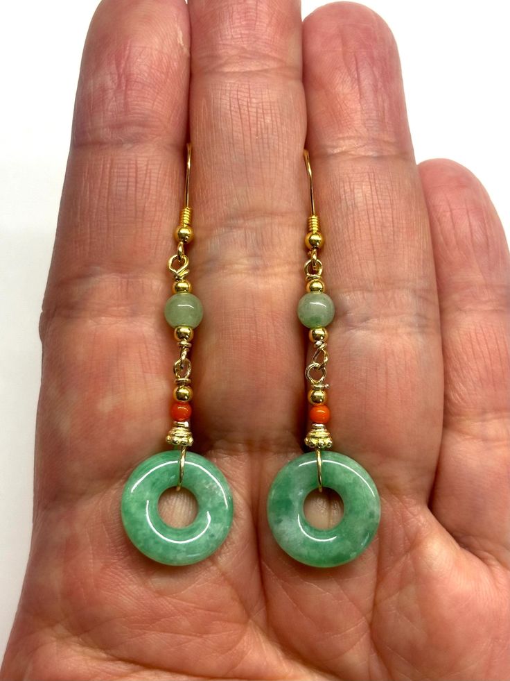 A pair of dangling earrings with a beautiful green jade donut safety buckles (平安扣), complemented by green jade beads and coral beads.  The two natural colour jade donuts are safety buckles. The Chinese safety buckle (平安扣) is shaped like a coin. The Chinese believed that money brought luck and safety, but wearing a coin was not attractive, so the lucky buckle was designed with materials like jade and agate to wear coins on their person. - made with natural colour jade donuts, jade beads, coral be Round Jade Jewelry With Matching Earrings, Elegant Jade Hoop Earrings, Single Green Round Earring, Green Single Round Earring, Elegant Round Earrings With Dangling Beads, Handmade Jade Hoop Earrings, Handmade Hoop Jade Jewelry, Handmade Jade Hoop Jewelry, Jade Dangle Earrings For Pierced Ears