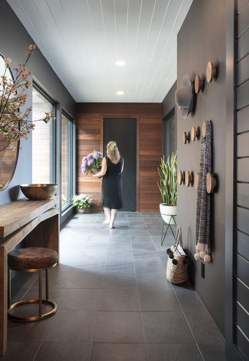 a woman is walking down the hallway in front of a mirror and potted plant