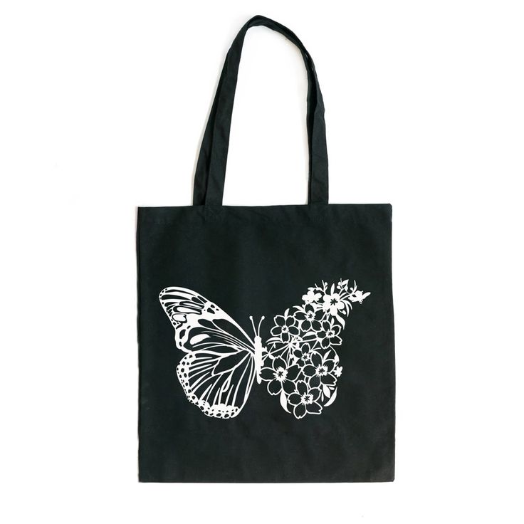 a black tote bag with a white butterfly on the front and flowers in the back