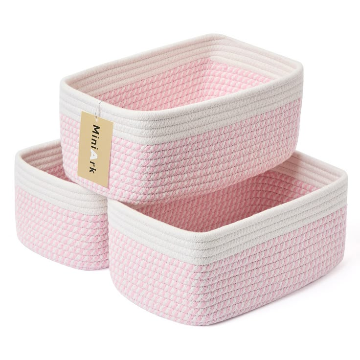 two pink baskets sitting next to each other on a white surface with a gold label