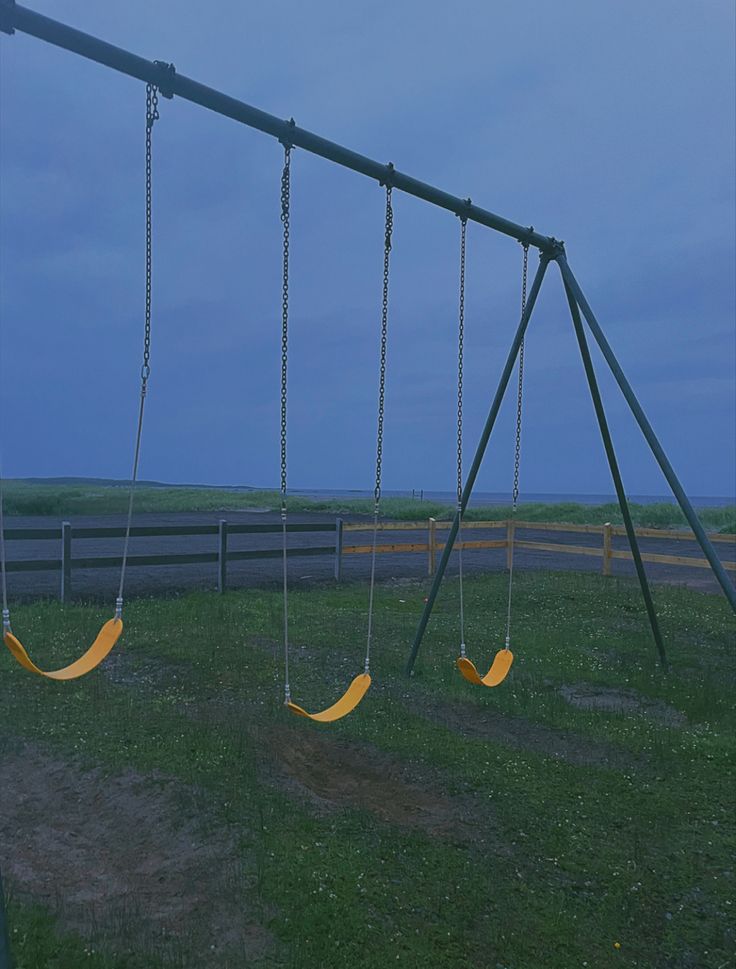 two swings in the grass near a fence