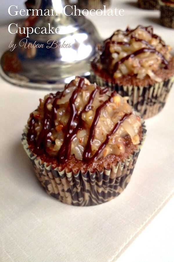 two cupcakes with chocolate drizzled on them sitting on a table