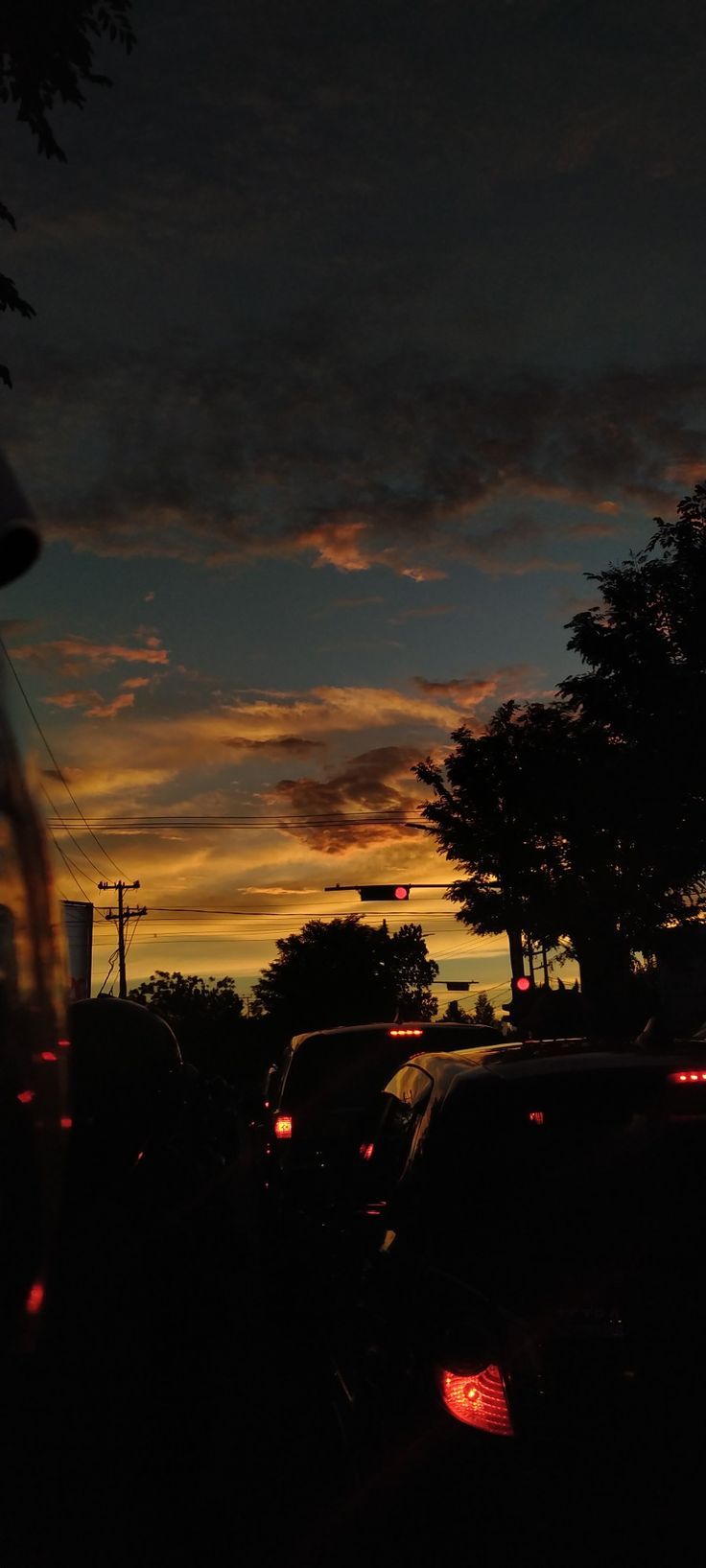 cars are parked on the side of the road at night, as the sun sets