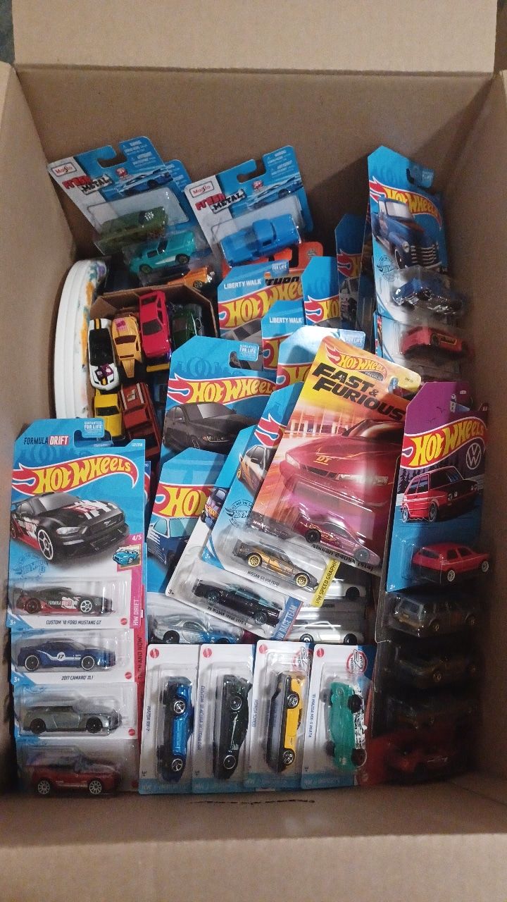 a cardboard box filled with hot wheels and other toy cars on top of each other