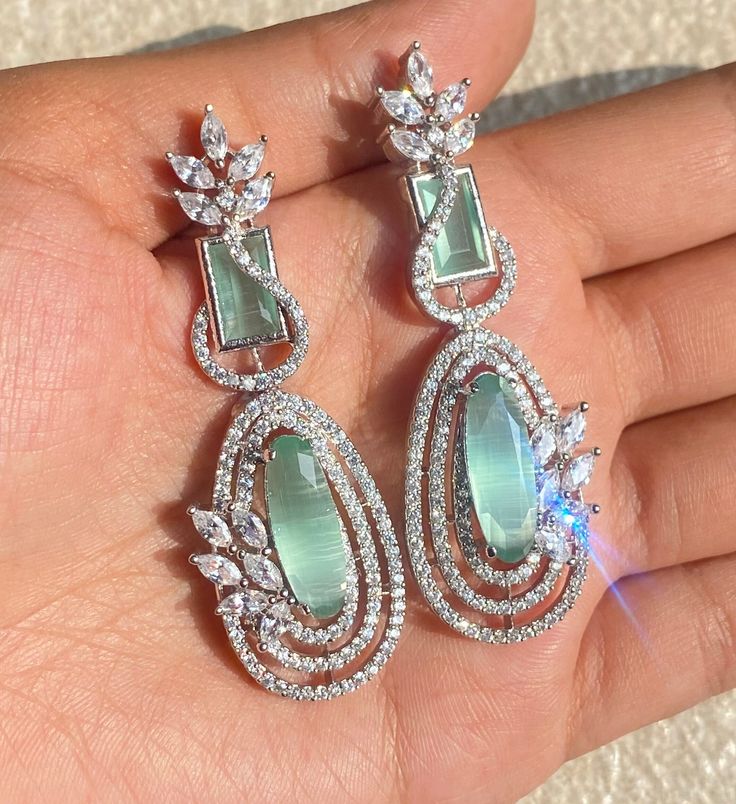 Mint Green Earrings featuring semi precious green stone and cz diamonds. Ideal to pair with your india western sarees and formal outfits. These earrings chendelier design will elevate your look. Perfect gift for her and gift for sister. *𝐏𝐑𝐎𝐃𝐔𝐂𝐓 𝐃𝐄𝐓𝐀𝐈𝐋* * 𝐌𝐚𝐭𝐞𝐫𝐢𝐚𝐥: Brass * 𝐏𝐥𝐚𝐭𝐢𝐧𝐠: White Rhodium Plated * 𝐒𝐭𝐨𝐧𝐞: AAA-quality CZ Diamond. *𝐃𝐈𝐌𝐄𝐍𝐒𝐈𝐎𝐍𝐒* * 𝐖𝐞𝐢𝐠𝐡𝐭: 8 gm each * Length: 2.4 Inches * Width: 0.7 Inches * 𝐂𝐥𝐨𝐬𝐮𝐫𝐞: Push Back 𝐕𝐢𝐬𝐢𝐭 ? Western Sarees, Mint Green Earrings, Mint Earrings, Formal Outfits, Chandelier Design, Earrings Green, Green Earrings, American Diamond, Pakistani Wedding