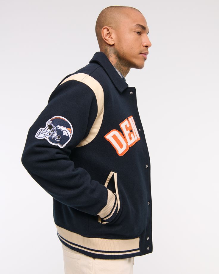 Classic bomber jacket in a soft faux wool fabric and relaxed-fit silhouette, featuring Denver Broncos varsity-inspired embroidered graphic patch details throughout, side pockets, snap-up front and tipping details at elastic cuffs and waistband. Game Day Long Sleeve Winter Track Jacket, Long Sleeve Track Jacket For Game Day In Winter, Winter Long Sleeve Track Jacket For Game Day, Collegiate Varsity Jacket With Logo Patch For College, College Varsity Jacket With Logo Patch, Urban Outerwear For Game Day In Fall, Urban Style Outerwear For Game Day In Fall, Collegiate Varsity Jacket With Logo Patch For Winter, Collegiate Varsity Jacket With Logo Patch For Fall