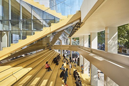 people are walking up and down the stairs in a building with many windows on each side