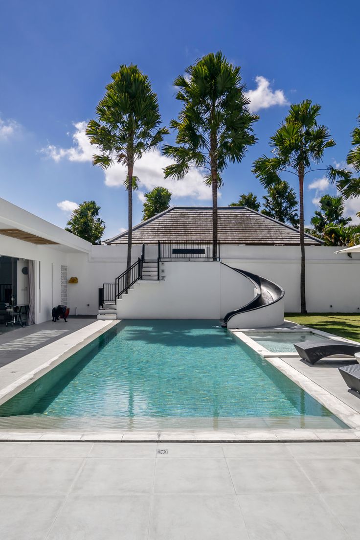 an outdoor swimming pool with lounge chairs and palm trees in the backgroung