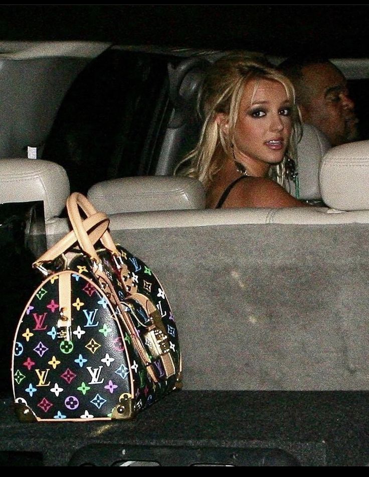 a woman sitting in the back seat of a car with a handbag next to her