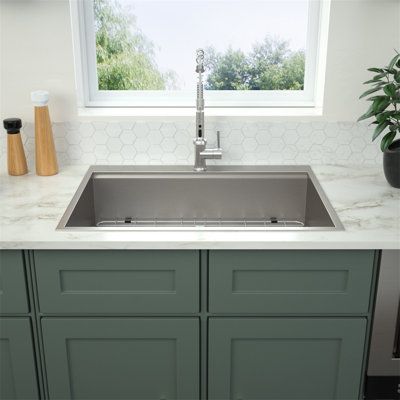 a kitchen sink sitting under a window next to a counter top with a potted plant