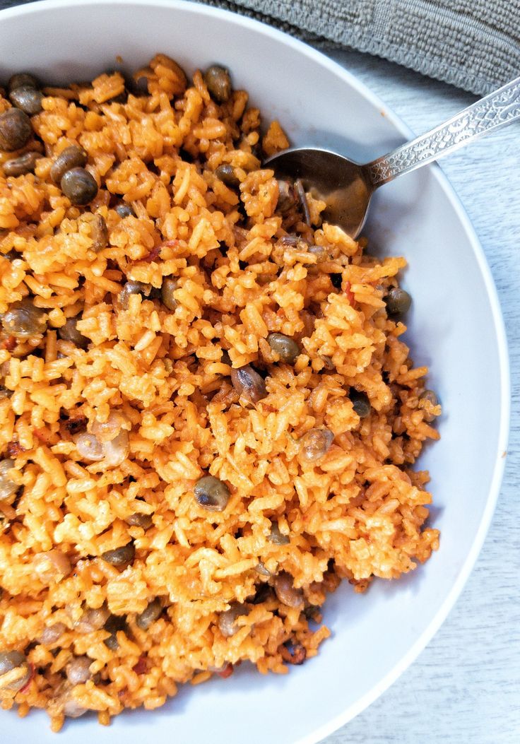 a white bowl filled with rice and beans on top of a table next to a spoon