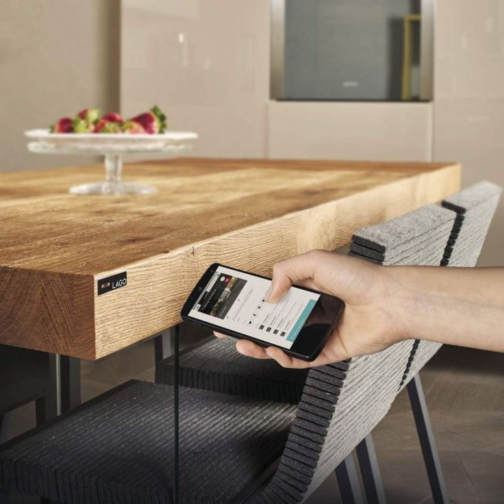 a person holding a cell phone at a wooden table