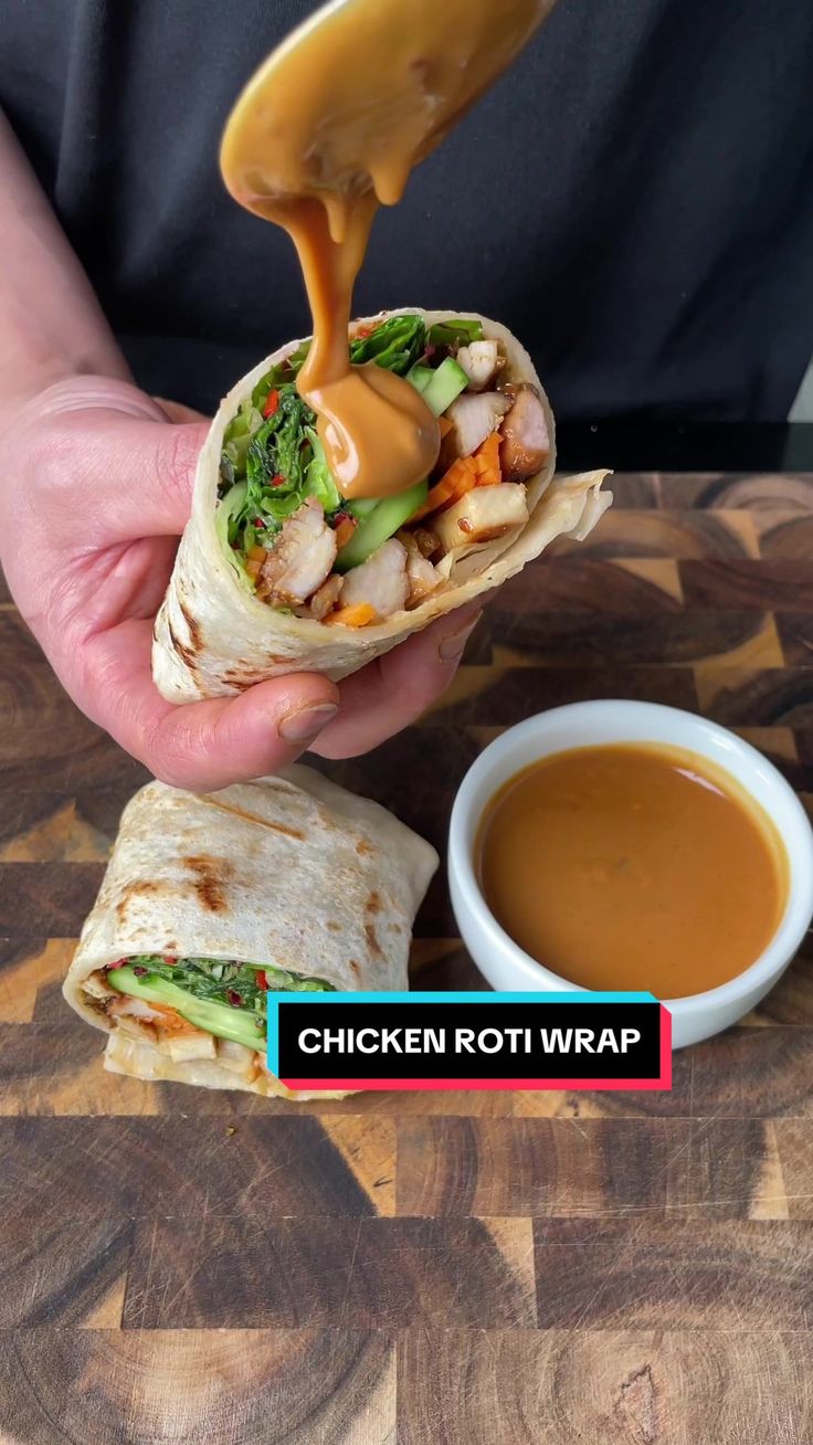 chicken roti wrap being held up with dipping sauce