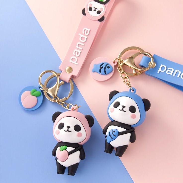 two key chains with panda bears on them sitting next to a pink and blue background