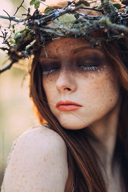 a woman with freckles on her face wearing a crown of branches over her head