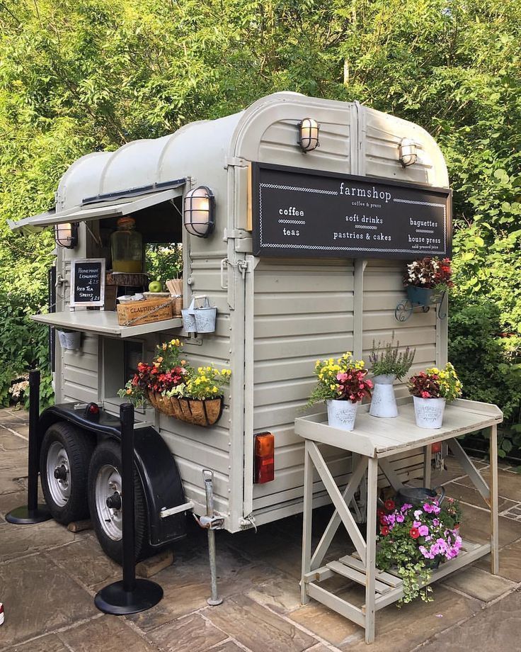 an old trailer converted into a coffee shop with potted plants and flowers on the side