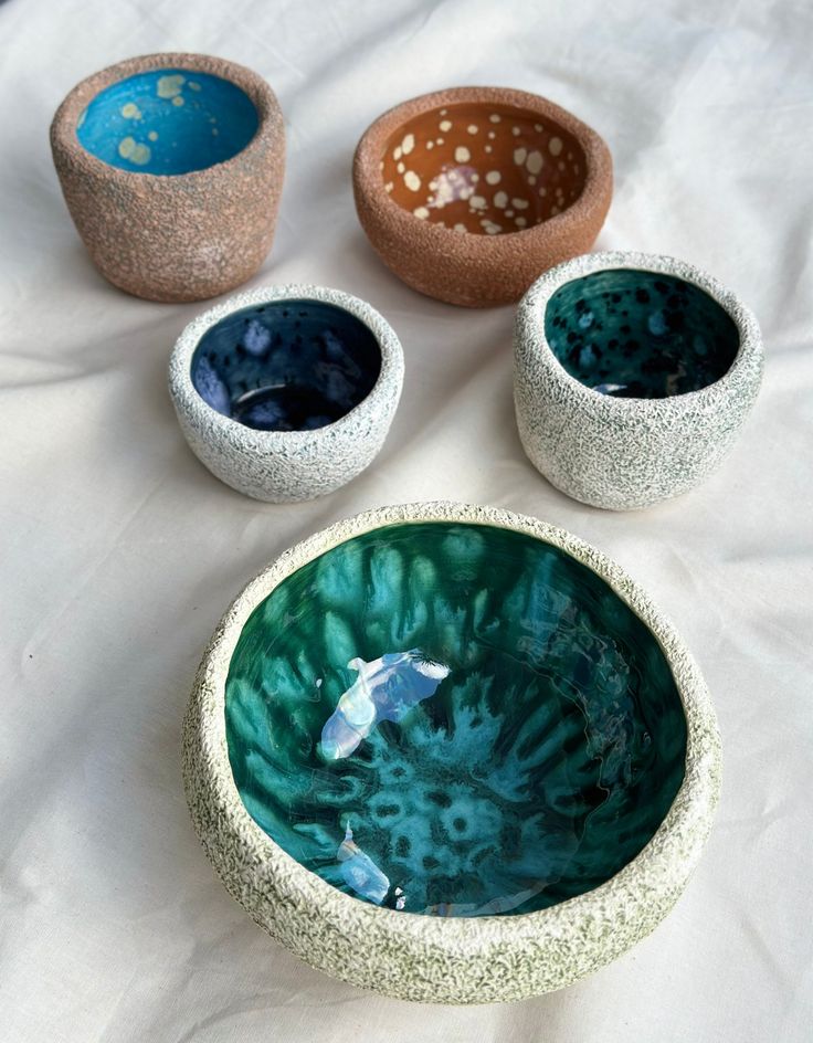 three bowls sitting on top of a white cloth covered table next to two fish bowls