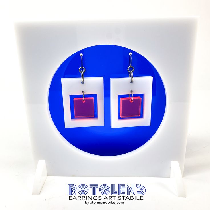 pair of earrings with red and white square design on display in front of blue background