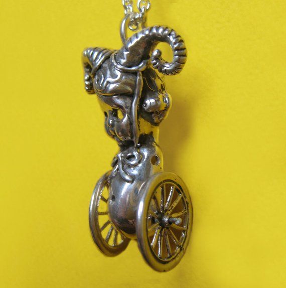 a silver necklace with an animal riding a bike