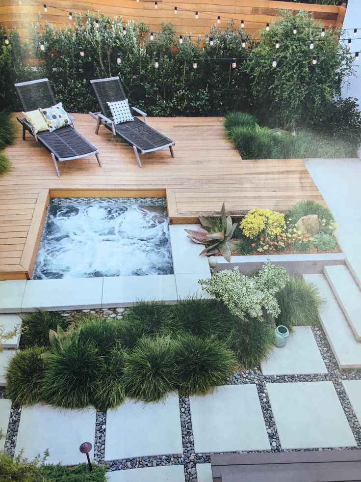 an aerial view of a hot tub surrounded by greenery and flowers in a backyard