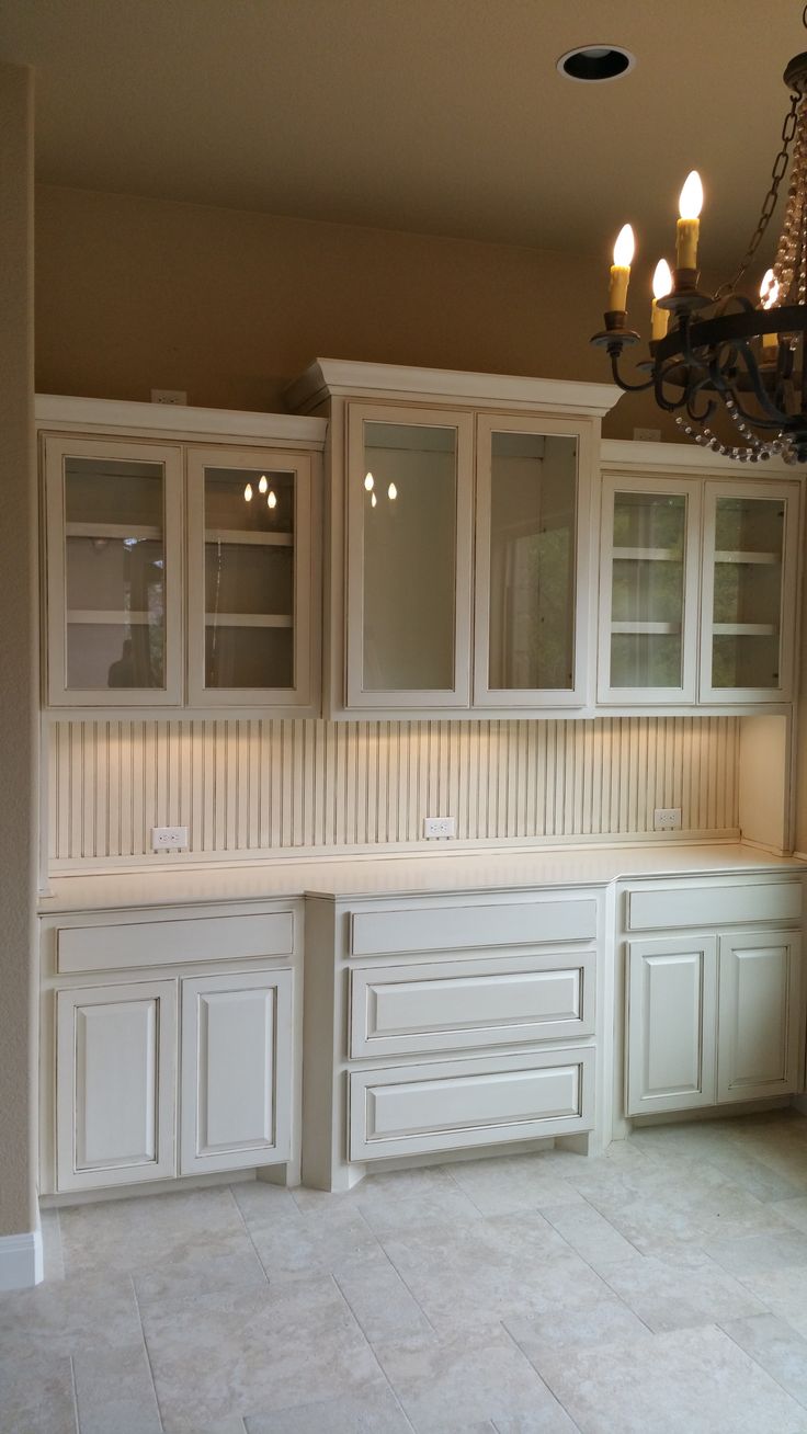 a chandelier hanging from the ceiling in a kitchen with white cabinets and drawers