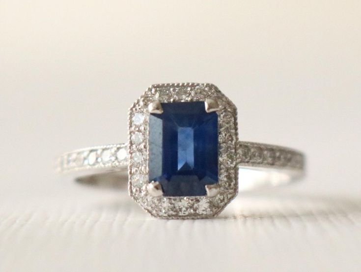 an engagement ring with a blue stone surrounded by white diamonds on a white tablecloth