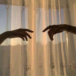 two hands reaching for each other in front of curtains