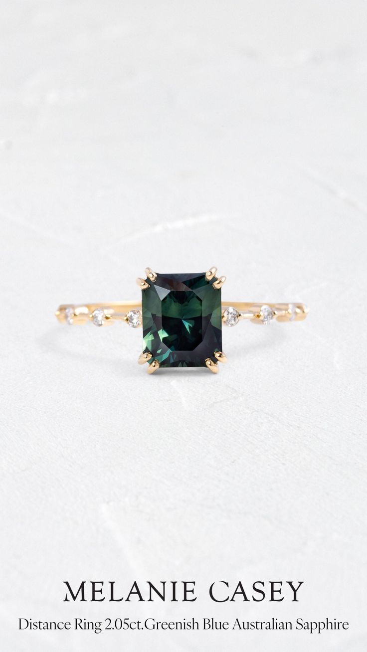 an emerald colored ring with diamonds on the sides and side stones in gold plated setting