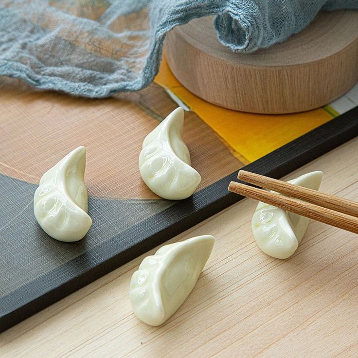 chopsticks are laying next to small white dumplings on a cutting board