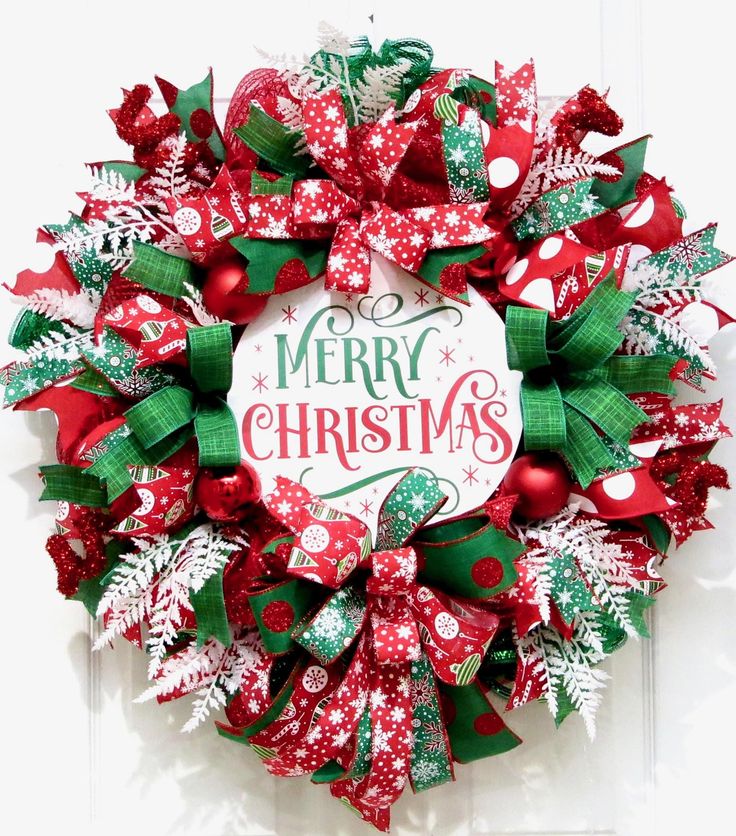 a red and green christmas wreath with merry lettering on the front door, decorated with bows