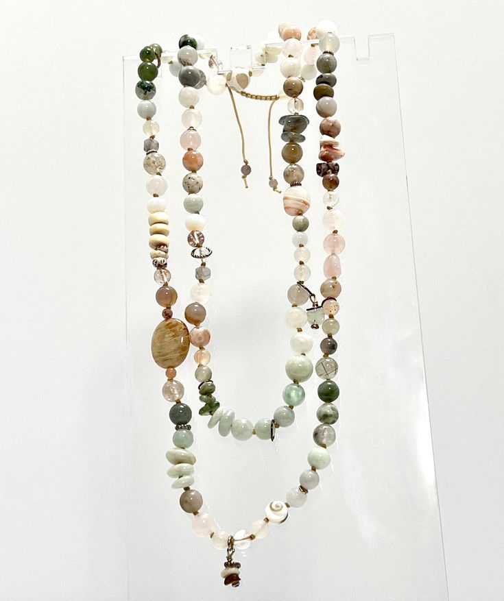 Our Cherishing Life's Gifts Mala Necklace surrounds you with a blissful mist of creams and whites, gentle greens, whispy pinks, and translucent light grays, providing a sense of soul searching and healing in a blanket of self-love.  This mala encourages you to release judgment and burdensome emotions, and enables you to consider your needs with peaceful perception and hopeful insights.  Jade works with Botswana Agate and Tibetan Agate to enhance tranquility, release negative thoughts, and encourage self-forgiveness and self-trust. Rose Quartz and Rhodochrosite restore trust and harmony in relationships, encouraging unconditional love, generosity, and kindness, and further boosts positive attitude, creativity, and innovation. Tourmalinated Quartz promotes self-confidence and diminishes fear Adjustable White Earthy Necklaces, White Adjustable Earthy Necklaces, Adjustable White Earthy Necklace, White Adjustable Earthy Necklace, Adjustable Hand Wrapped Necklaces For Layering, Adjustable Hand-wrapped White Necklace, Cherish Life, Bright Minds, Tourmalinated Quartz