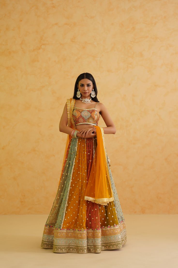 Multicolored Lehenga Set | Deepika Chadha Deepika Chadha's stunning Multi colored net fabric lehenga, beautifully adorned with a stylish brocade blouse. The beautiful colors adds a touch of glamour and sophistication to your look, while the net texture ensures you feel comfortable all day or night long. It is styled with orange net Dupatta to complete the look. Included in Purchase: Lehenga, Blouse & Dupatta Set Product Specification Color: Orange Fabric: Brocade, Net Neckline: Spaghetti Strap Occasion: Bridal, Engagement, Formal Event Designer: Deepika Chadha Work: Hand Embroidery Care Instructions: Dry Cleaning only, No Flat Ironing on Hand Embroidery *Jewelry sold separatelyCustomization options:Can be customized in any color or blouse style Note: A stylist will contact you to confirm m Festive Multicolor Organza Pre-draped Saree, Designer Multicolor Lehenga With Zari Work, Multicolor Designer Dress With Dupatta, Designer Multicolor Dresses With Sheer Dupatta, Multicolor Dress With Sheer Dupatta For Festive Occasions, Festive Multicolor Dress With Sheer Dupatta, Orange Anarkali Lehenga In Organza, Anarkali Orange Organza Lehenga, Bollywood Style Orange Organza Choli