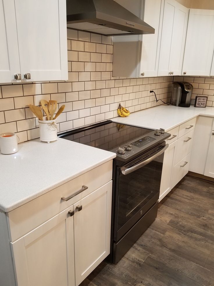 a kitchen with white cabinets and black appliances