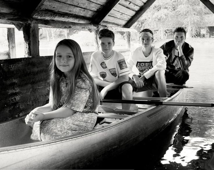 four young people are sitting in a canoe