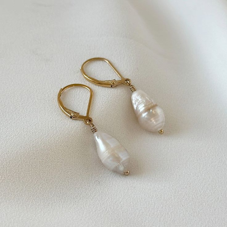 "Introducing Baroque Pearl Earrings in a mesmerizing combination of gold and fresh water pearls. These dangle drop earrings are perfect for the modern woman who loves a touch of elegance in her minimalist style. The beautiful Baroque pearls gracefully dangle from the gold hooks, creating a chic and timeless accessory. Ideal for anniversary celebrations, weddings, or any special occasion, these earrings will make a stunning statement. Give the gift of refined beauty with these Baroque Pearl Minim Teardrop 14k Gold-filled Pearl Earrings For Anniversary, Teardrop 14k Gold Filled Pearl Earrings For Anniversary, 14k Gold Filled Teardrop Pearl Earrings For Anniversary, 14k Gold Filled Pearl White Dangle Pearl Earrings, 14k Gold Filled Pearl Drop Earrings For Anniversary, Minimalist Teardrop Baroque Pearl Earrings, 14k Gold-filled Pearl Drop Bridal Earrings, 14k Gold Filled Pearl Drop Bridal Earrings, Elegant Teardrop Pearl Earrings In 14k Gold Filled