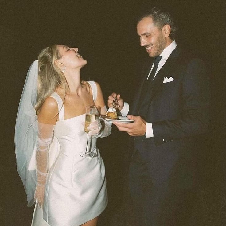 a man in a tuxedo standing next to a woman in a white dress