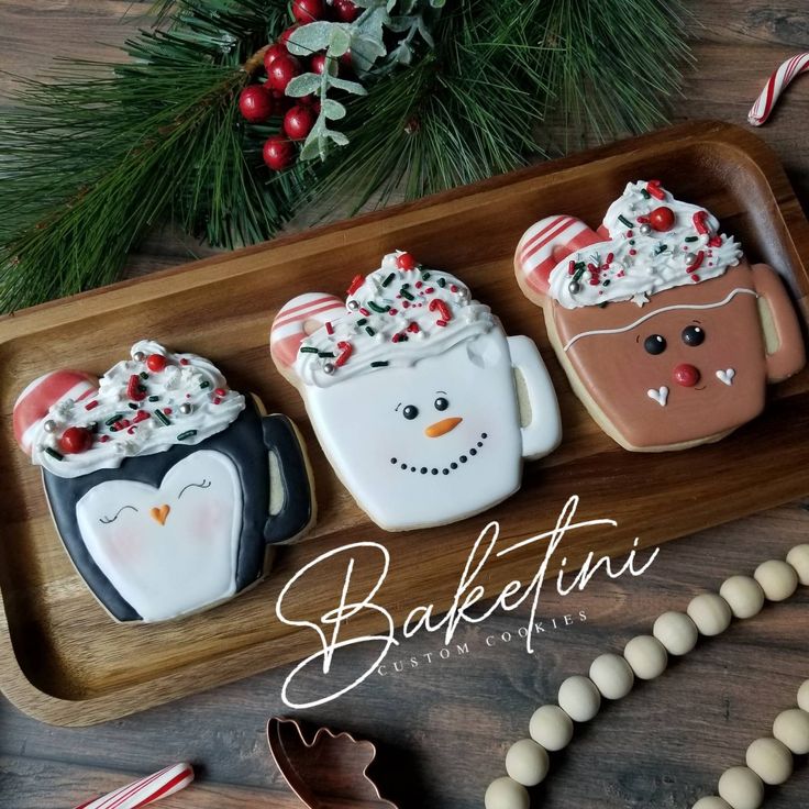 three decorated cookies sitting on top of a wooden platter next to candy canes