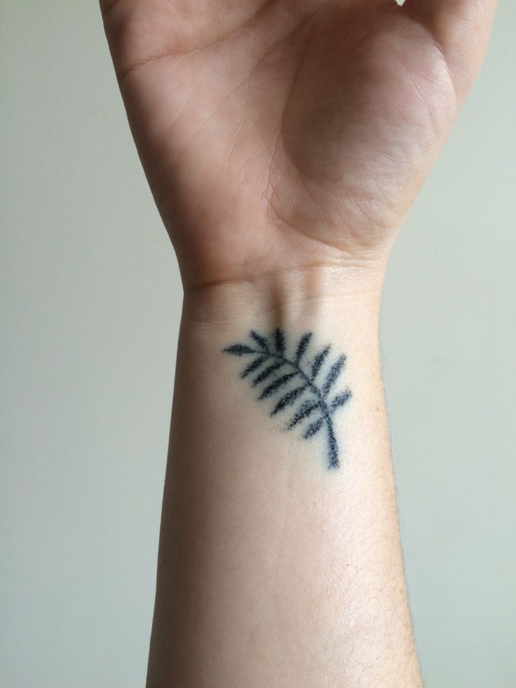 a person's wrist with a small tattoo design on the left side of their arm