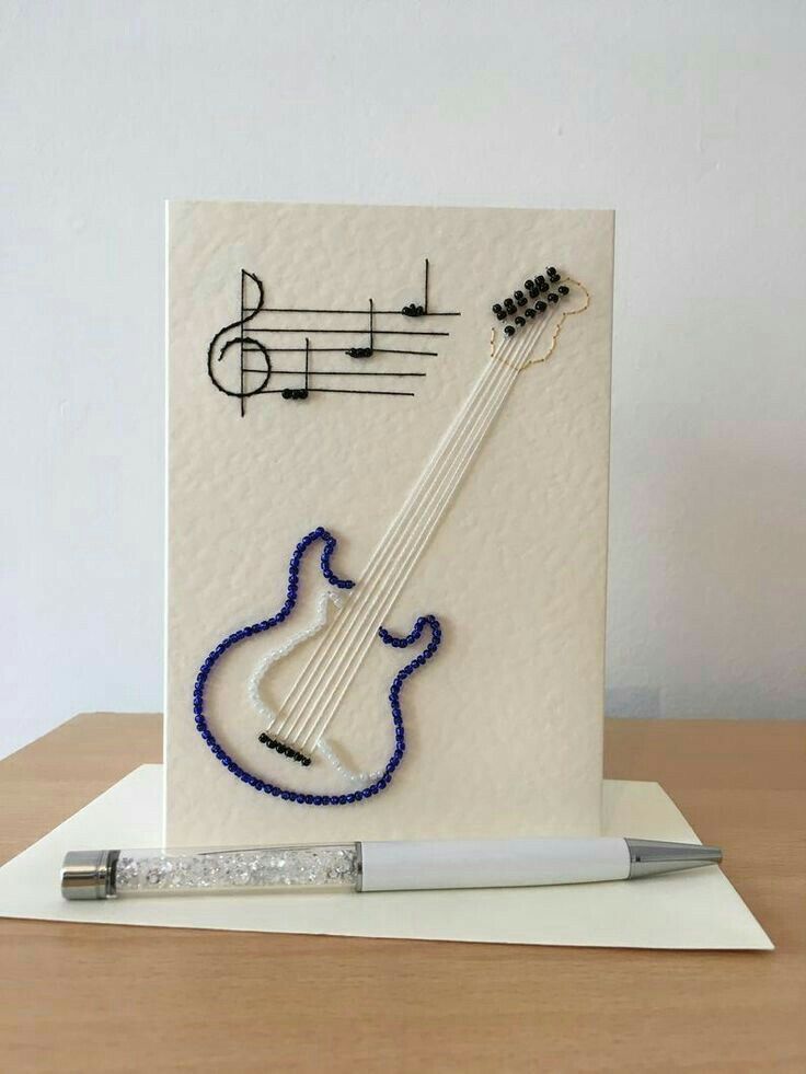 a white card with a guitar and musical notes on it, next to a pen