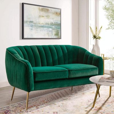 a living room with a green velvet couch and coffee table in front of a large window