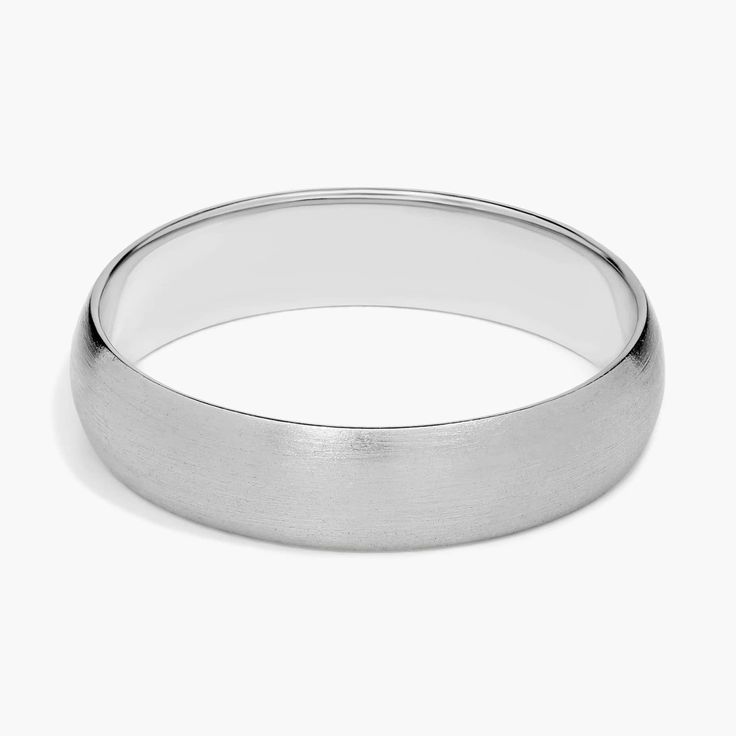 a white gold wedding ring on a plain surface with a slight edge, in the shape of an oval